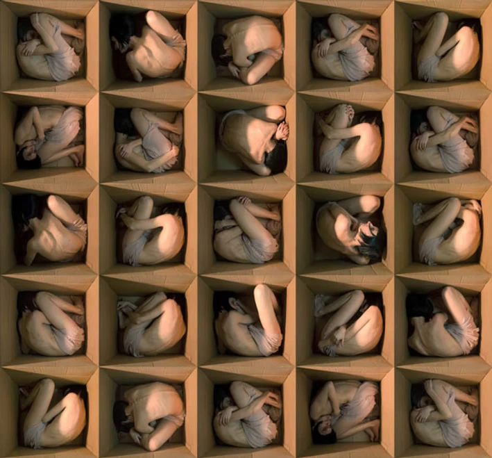 A large collection of nearly nude figures is enclosed in open wooden boxes.